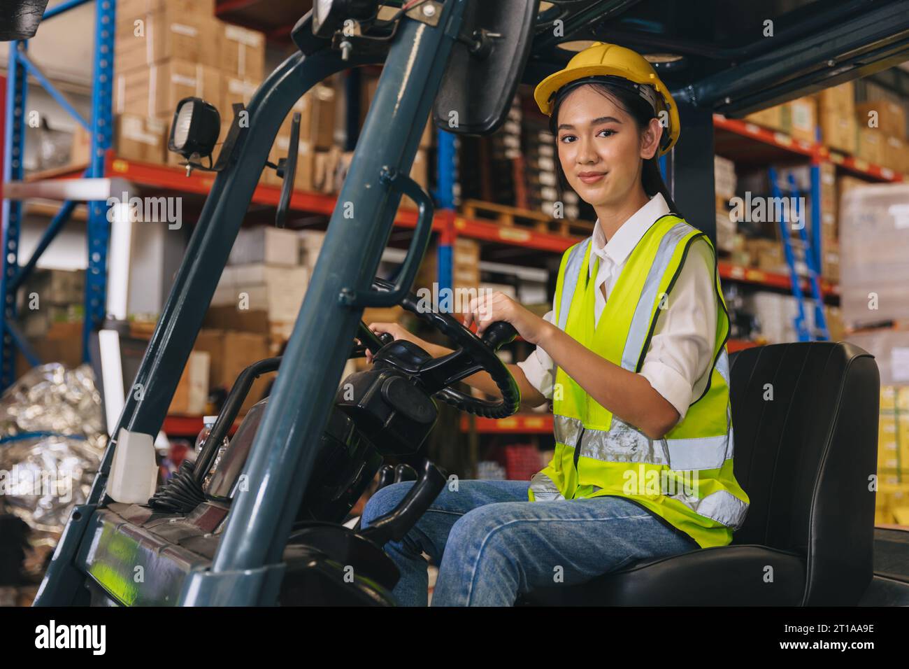 Forklift driver young staff lady worker in warehouse logistics loading cargo products storage industry Stock Photo
