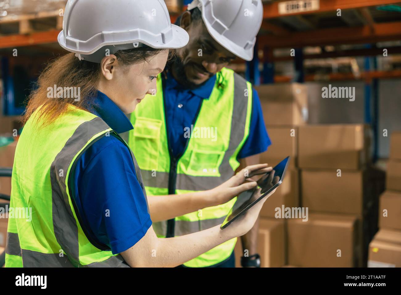 Warehouse cargo team training new staff using inventory management technology system in wireless tablet working teamwork together Stock Photo