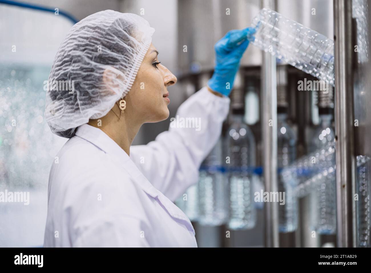 women worker working in hygiene factory in clean line drinking water Pet plastic bottle production Stock Photo