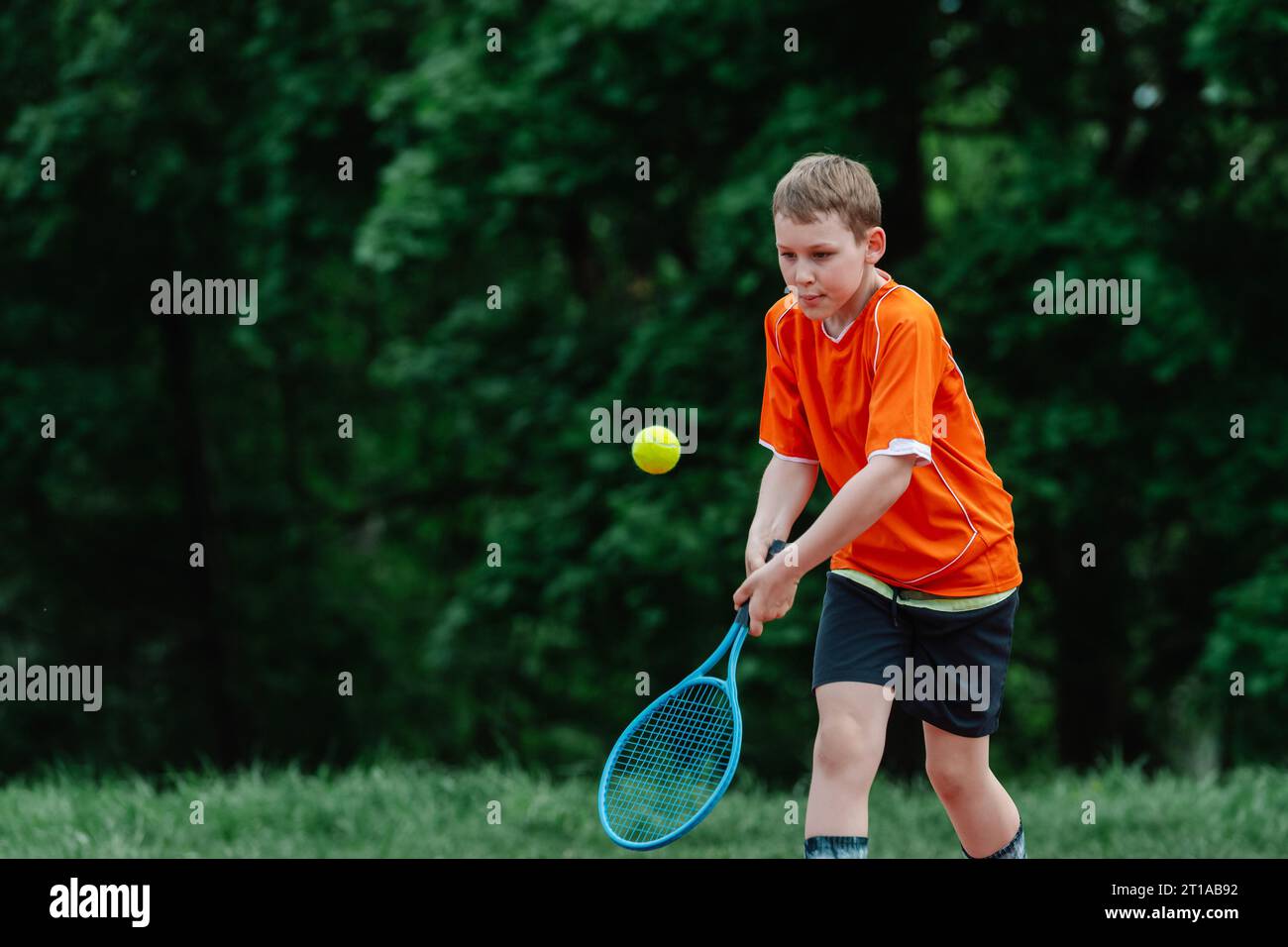 Child with tennis racket on tennis court. Training for young kid, healthy children. Horizontal sport theme poster, greeting cards, headers, website an Stock Photo