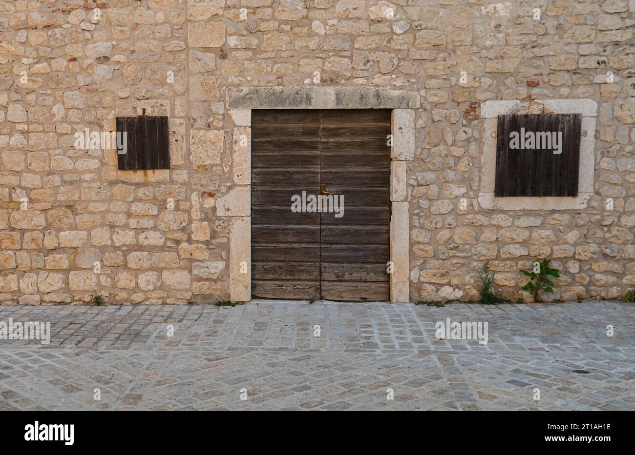 old wooden door in the wall made from limestone Stock Photo