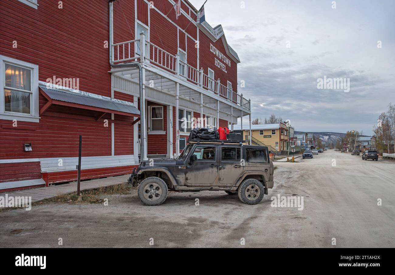 Dawson City, Yukon, Canada – October 05, 2023: Muddy Jeep with rooftop provisions parked outside the Downtown Hotel Stock Photo