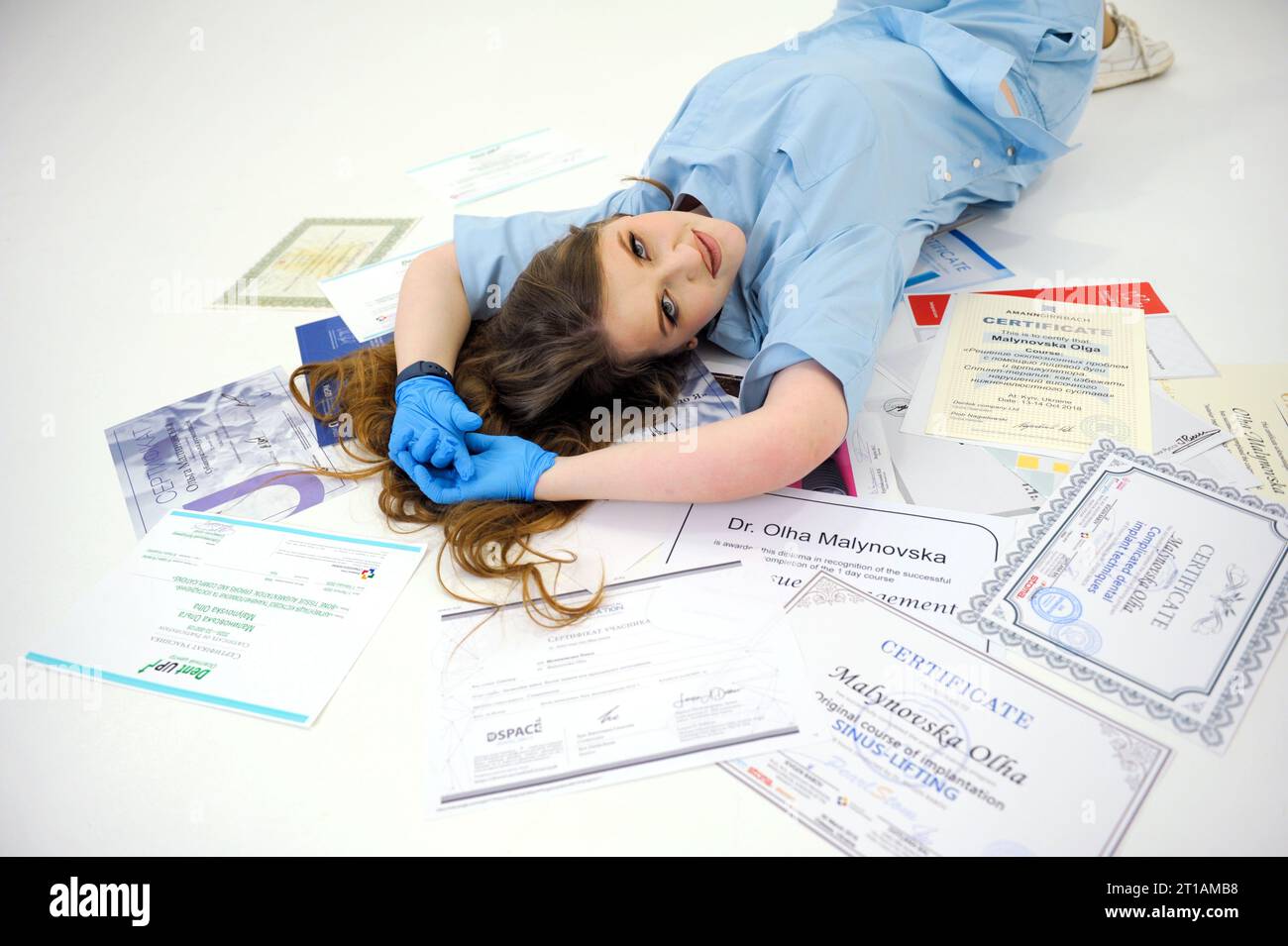 beautiful woman doctor in gloves and blue medical suit lies on diplomas