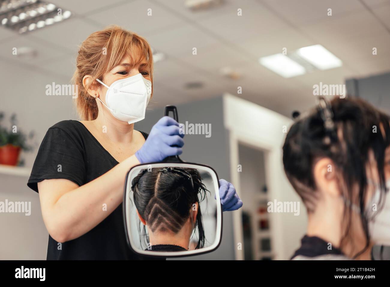 Hairdresser with mask showing the result of the cut in a mirror
