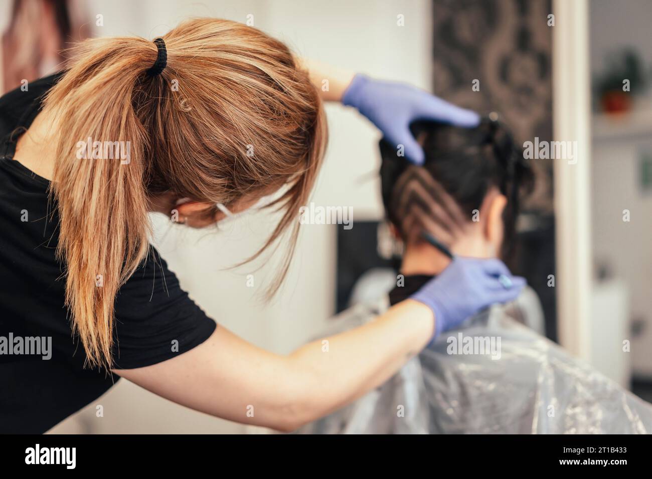 Hairdresser with mask shaving and making triangular drawings to the