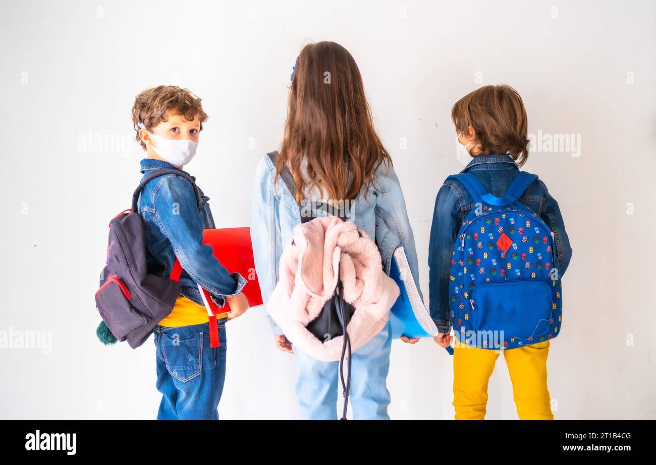 Three children with face masks ready to go back to school. New ...