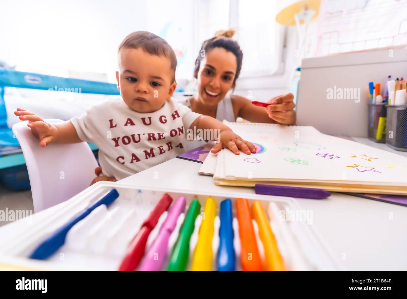 Young Caucasian mother playing with her in the room with toys. Baby less than a year learning the first lessons of her mother. Painting with color Stock Photo