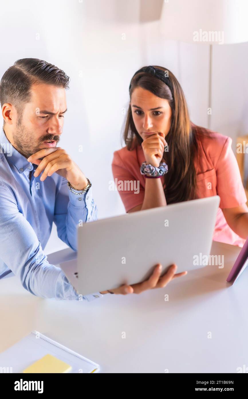 A couple teleworking at home, difficulties of the new work normalities, Caucasian couple working at a table with computers in the living room of Stock Photo
