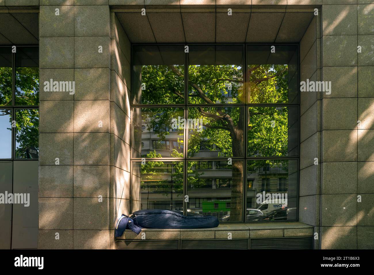 Homeless person in a window recess of an office building, Paris, France Stock Photo