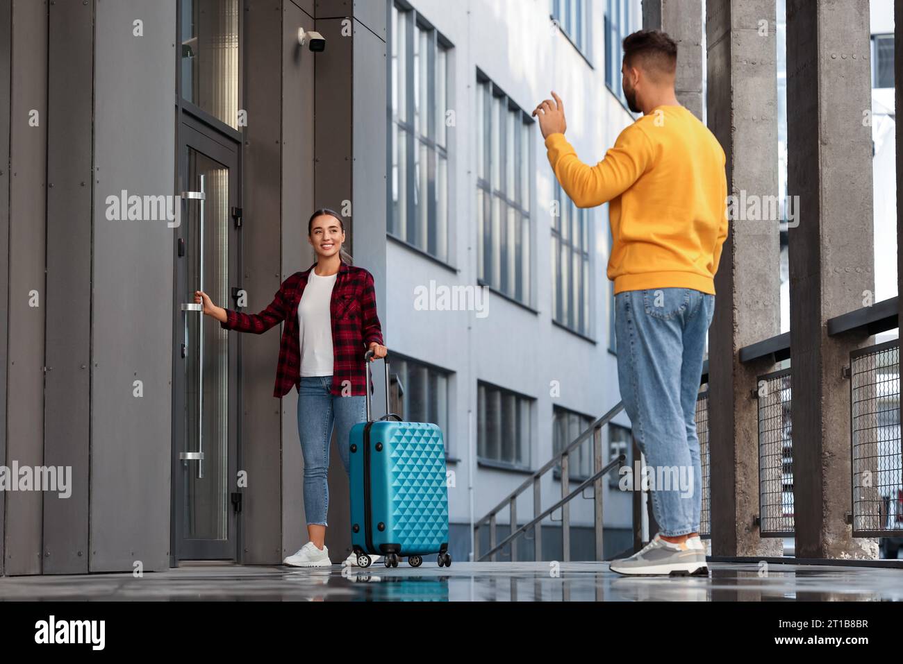 Long-distance relationship. Man waving to his girlfriend with suitcase ...