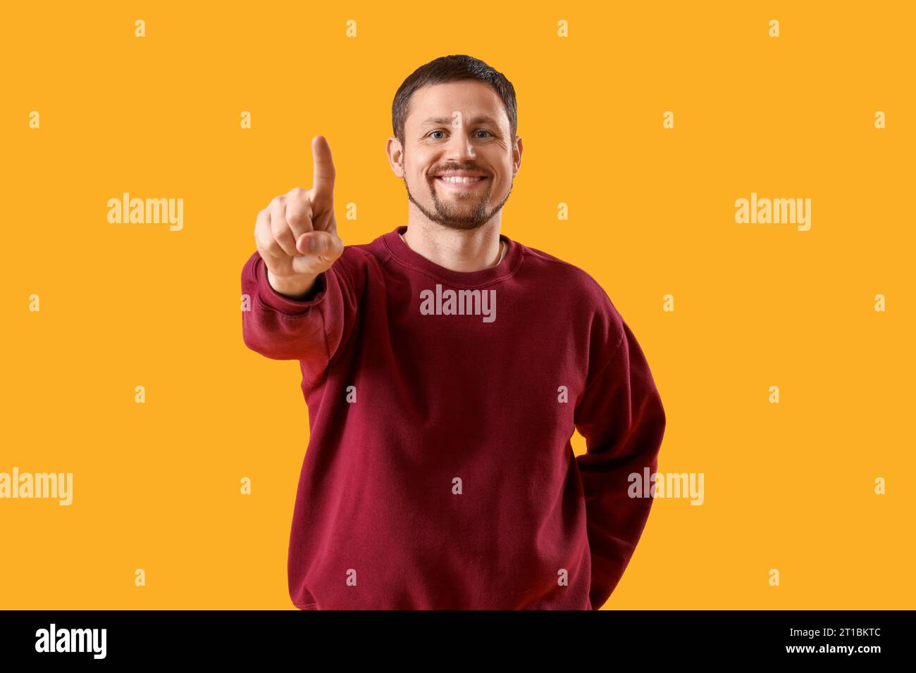 Handsome man using virtual screen on yellow background Stock Photo
