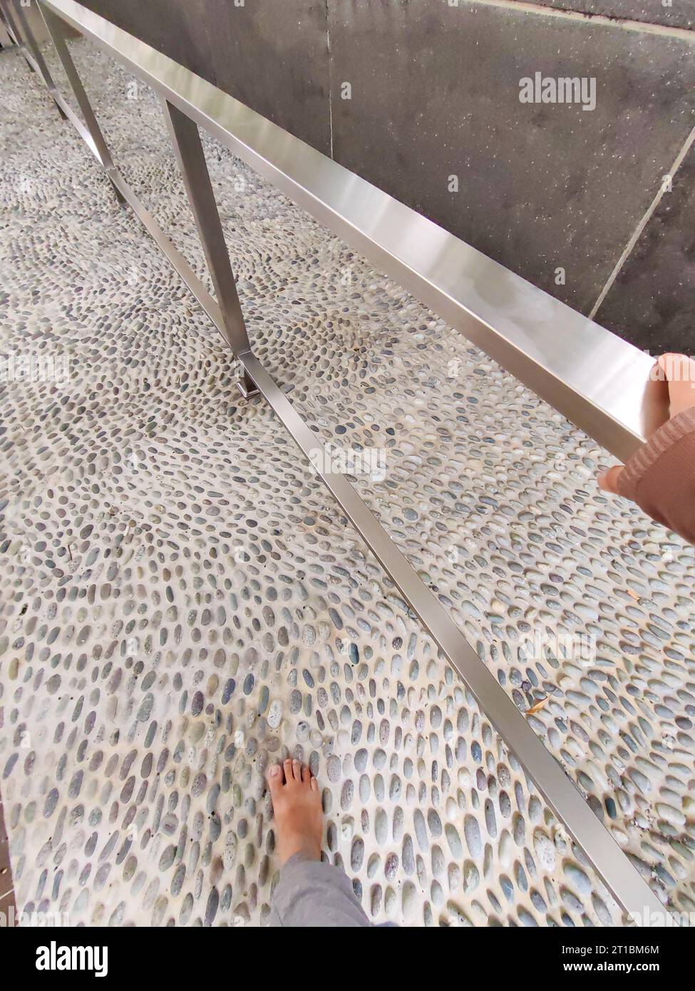 POV barefoot feet stepping on stones, foot reflexology at the park