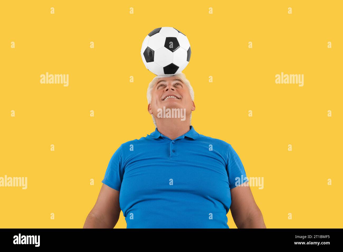 Mature man with soccer ball on yellow background Stock Photo - Alamy