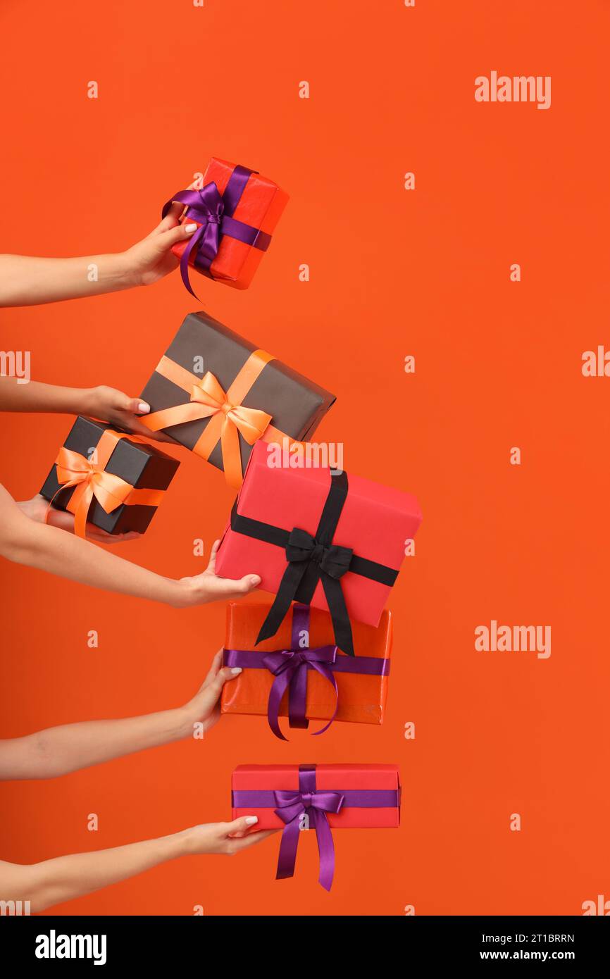 Women with Halloween gifts on orange background Stock Photo
