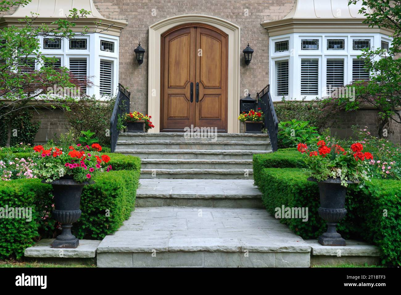 Flagstone steps leading to elegant wood grain double front door of house Stock Photo