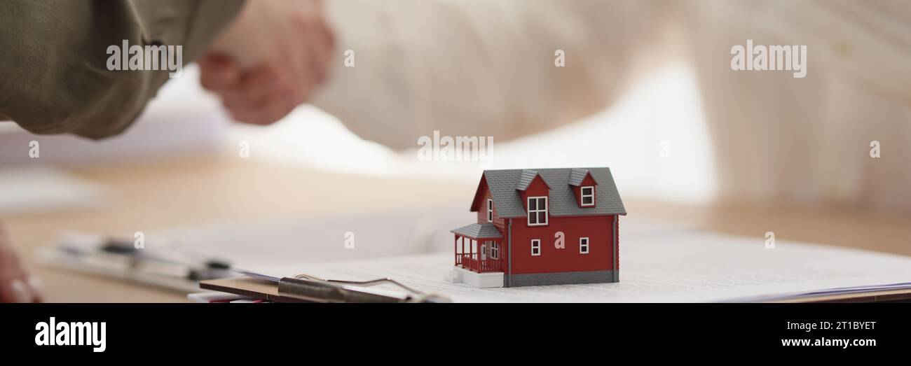 Female real estate agent gives key to house to client Stock Photo - Alamy