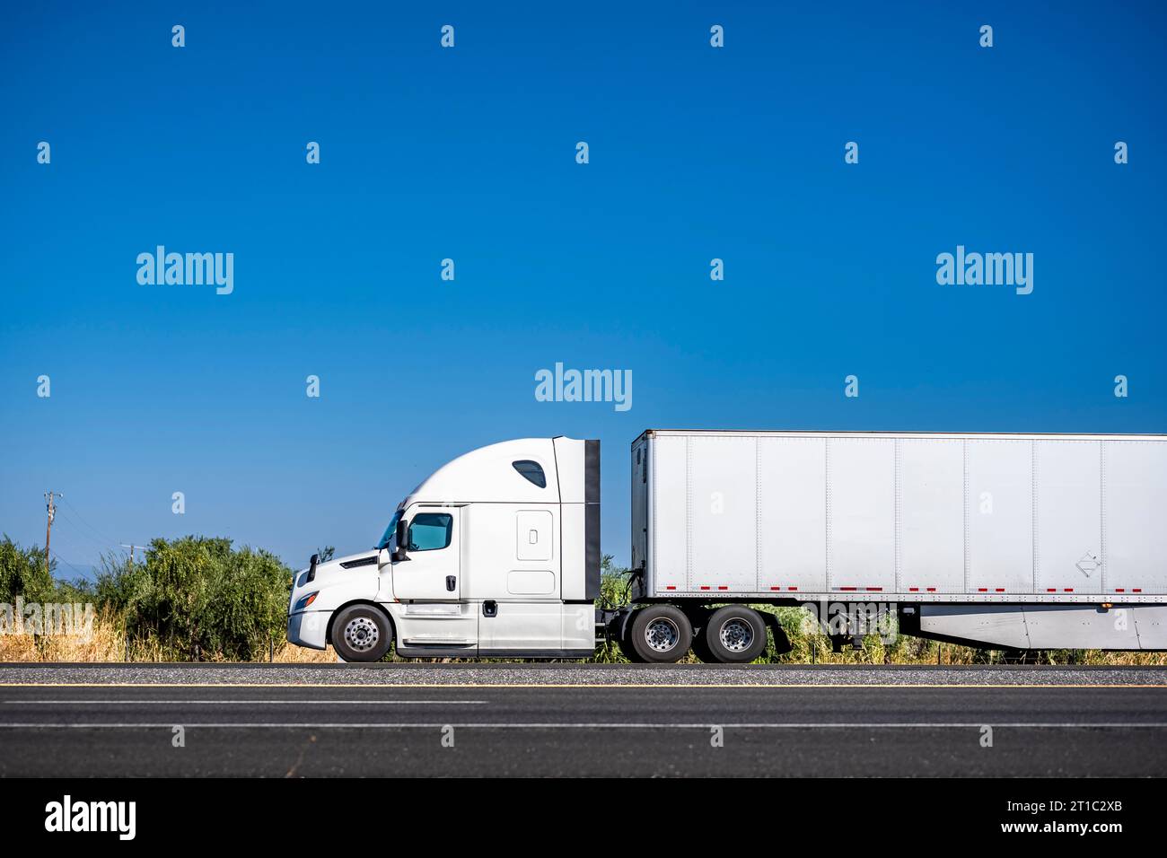 White industrial carrier big rig semi truck tractor with extended cab for truck driver rest  transporting commercial cargo in dry van semi trailer run Stock Photo