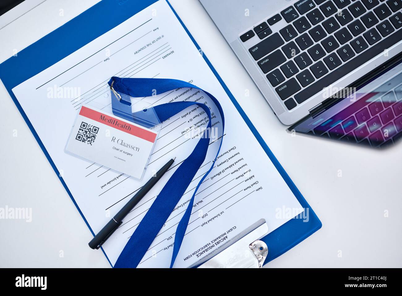 Above shot, insurance form and documents with laptop, name tag and form
