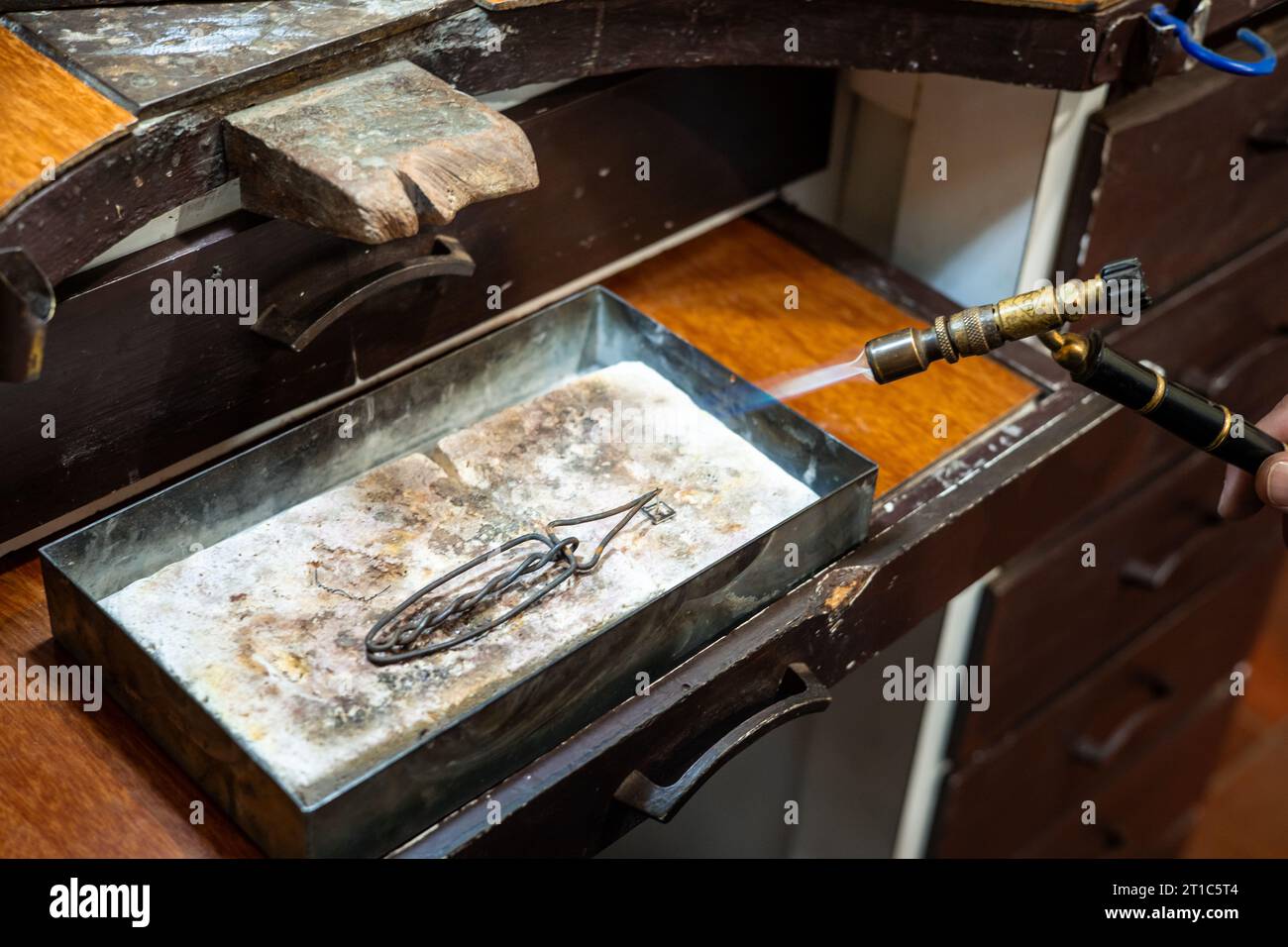 Jeweler melting silver metal with open flame blow torch welding