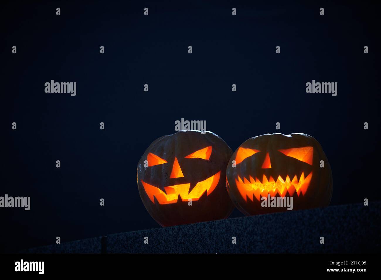 Two glowing Halloween Pumpkins on a dark background. Stock Photo