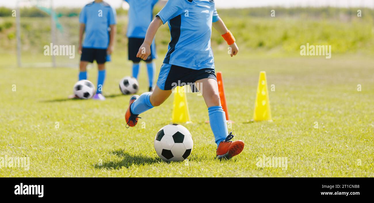 Young Football Players Kicking Ball on Practice Drill. Boys Running Balls on Training Drill. Child Kicking Ball on Slalom Drill. Group of School Footb Stock Photo