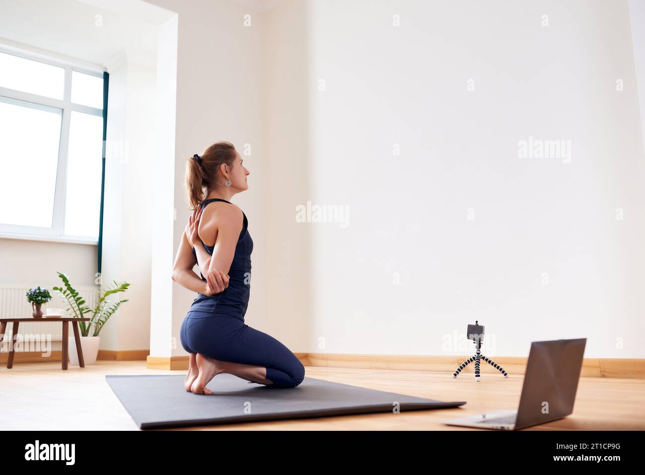 Yoga Using Machine Woman doing yoga online. Computer and camera in her living room ...