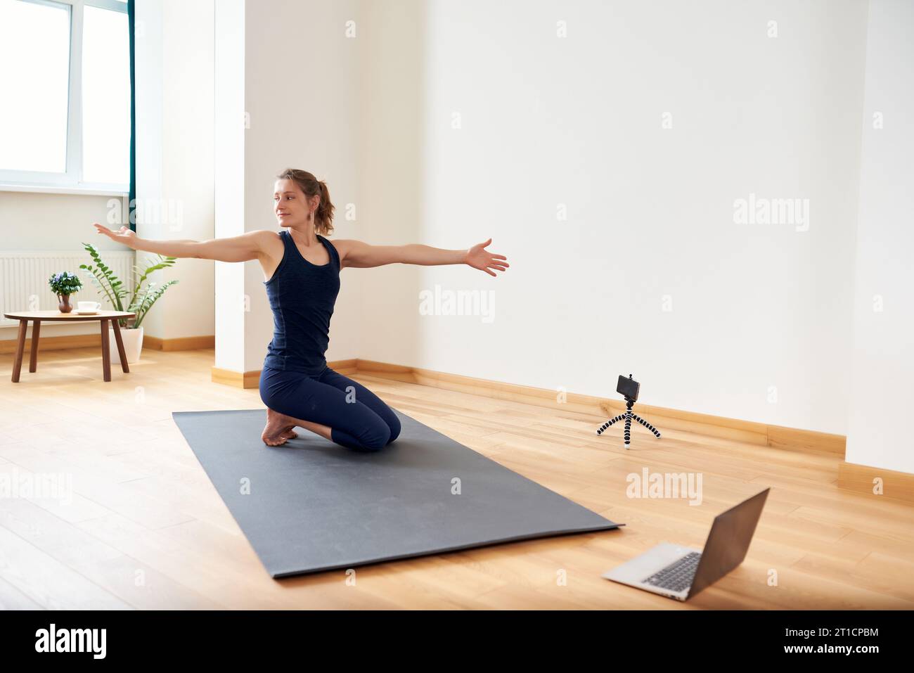 Yoga Using Machine Woman doing yoga online. Computer and camera in her living room ...