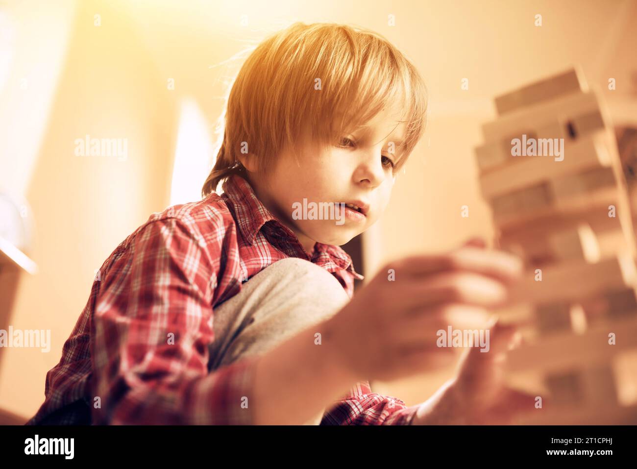 Preschool cute boy playing in a table game with wooden blocks at home