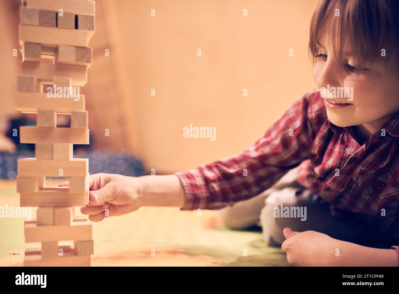 Preschool cute boy playing in a table game with wooden blocks at home