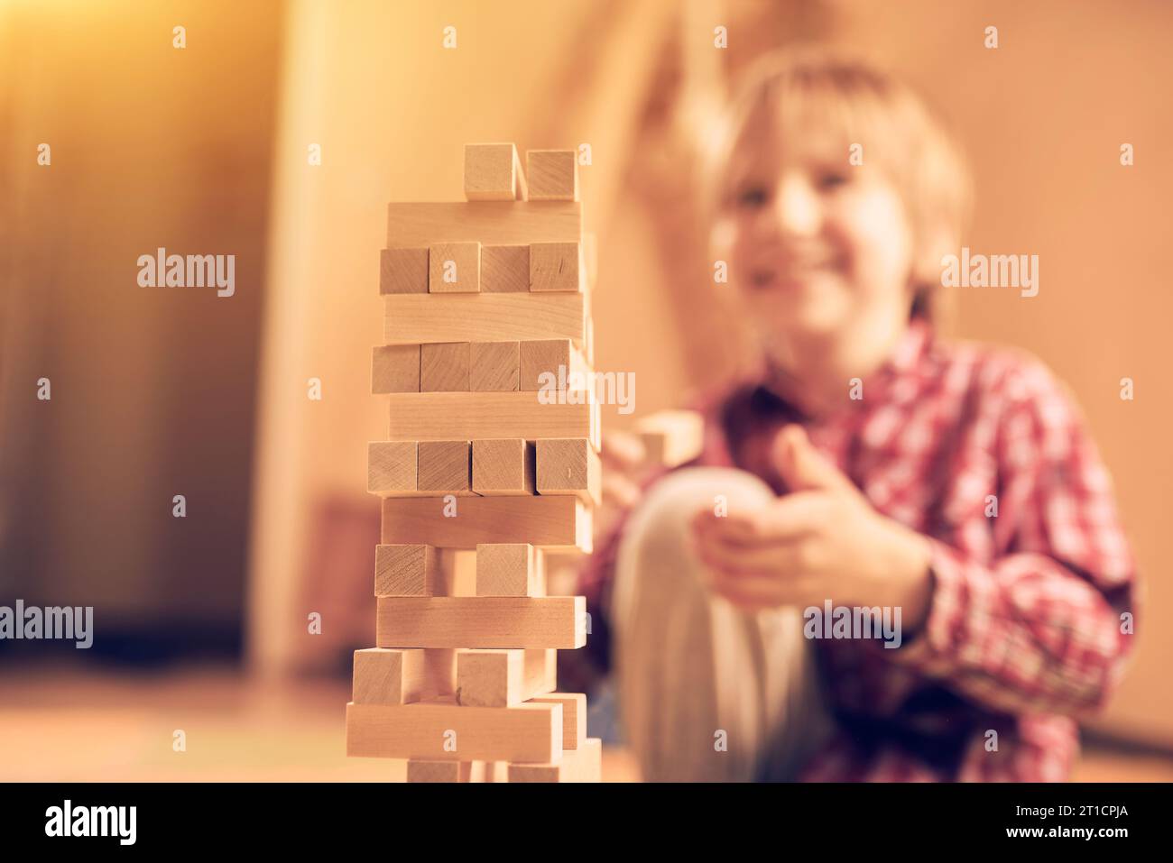 Preschool cute boy playing in a table game with wooden blocks at home