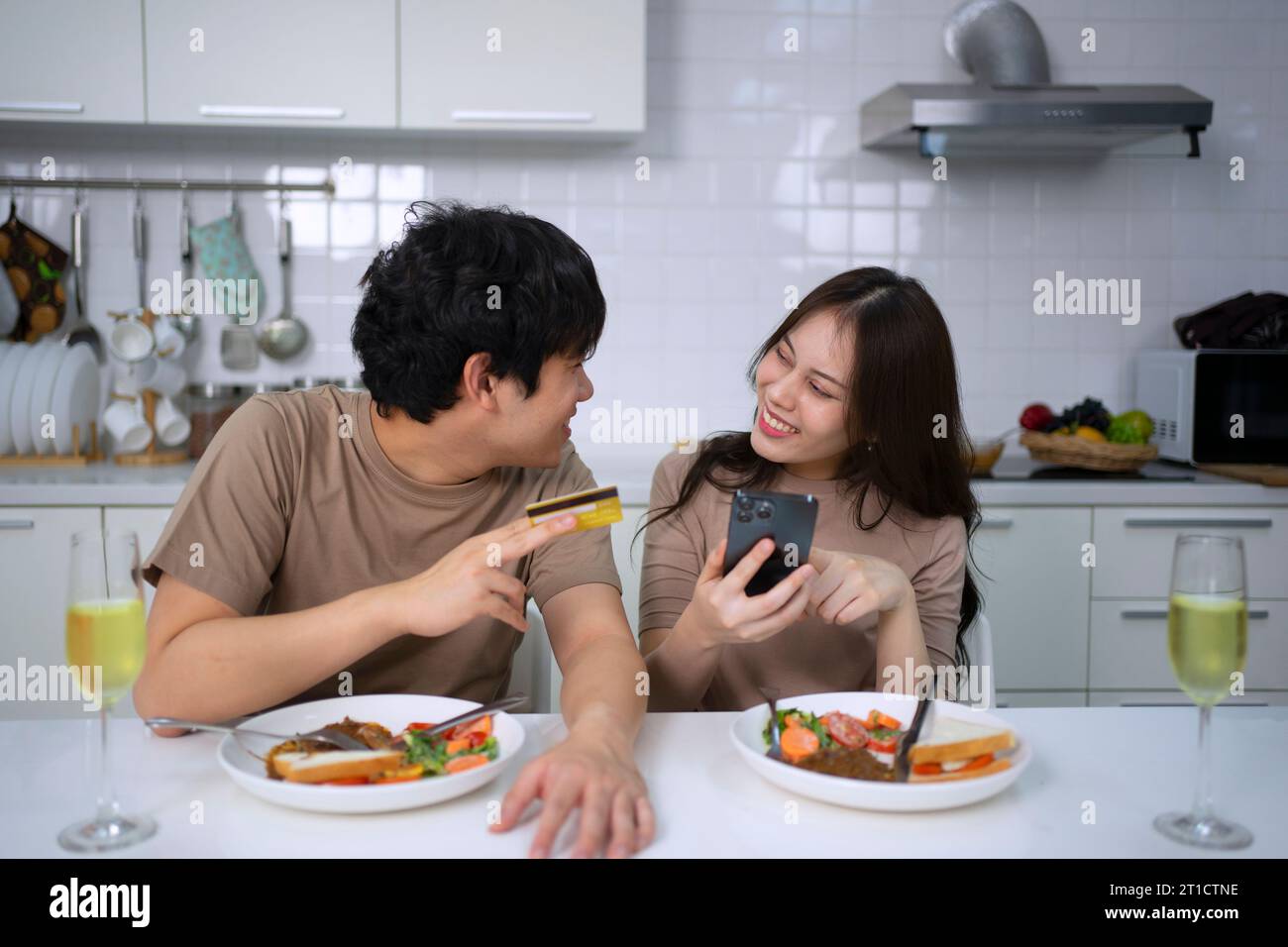Young couple is shopping online in kitchen. Lifestyle and leisure activity concept. Stock Photo
