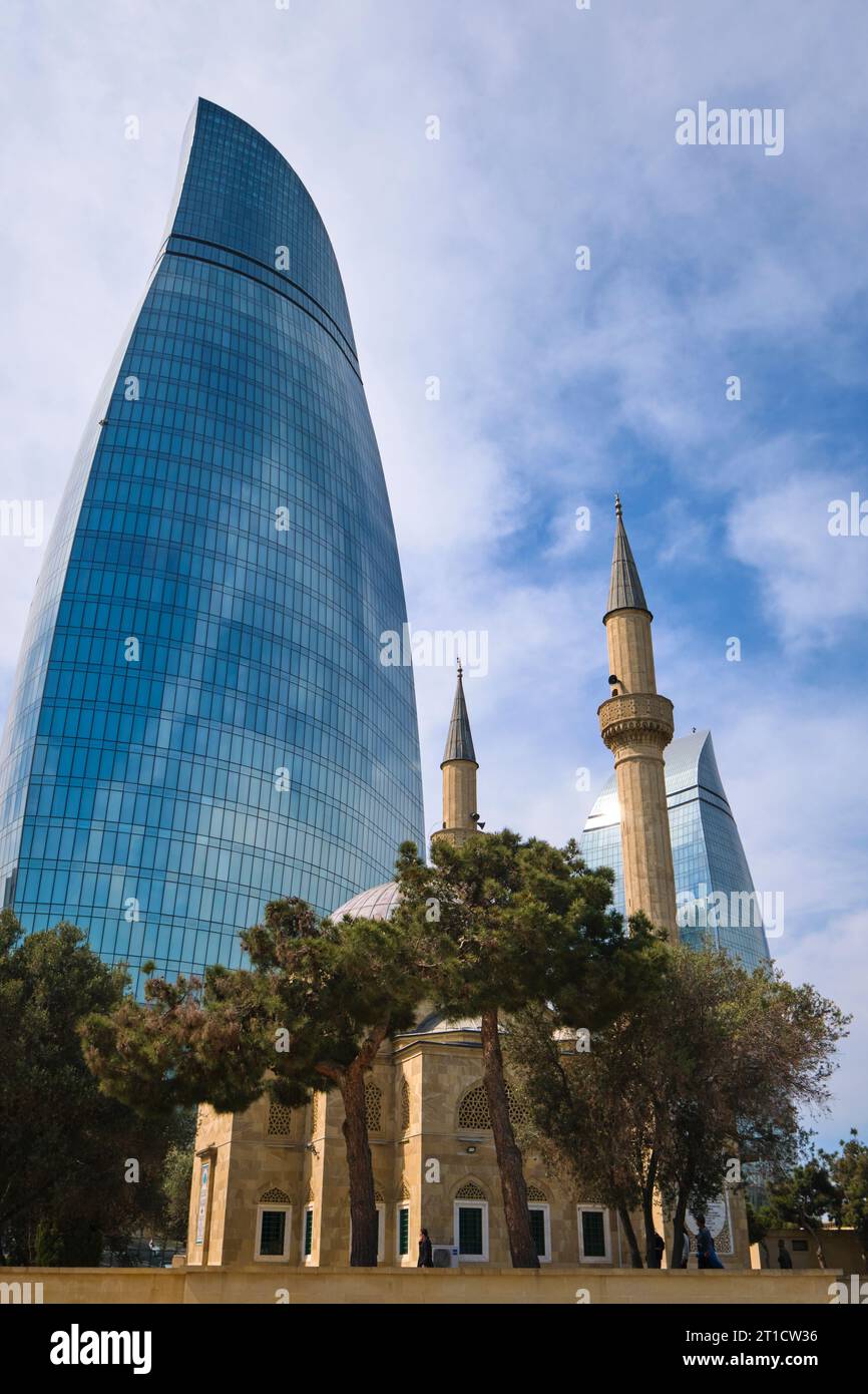 A view of the Muslim, traditional, Alley of Martyrs Mosque with the iconic Flame Towers complex in the background. In Baku, Azerbaijan. Stock Photo