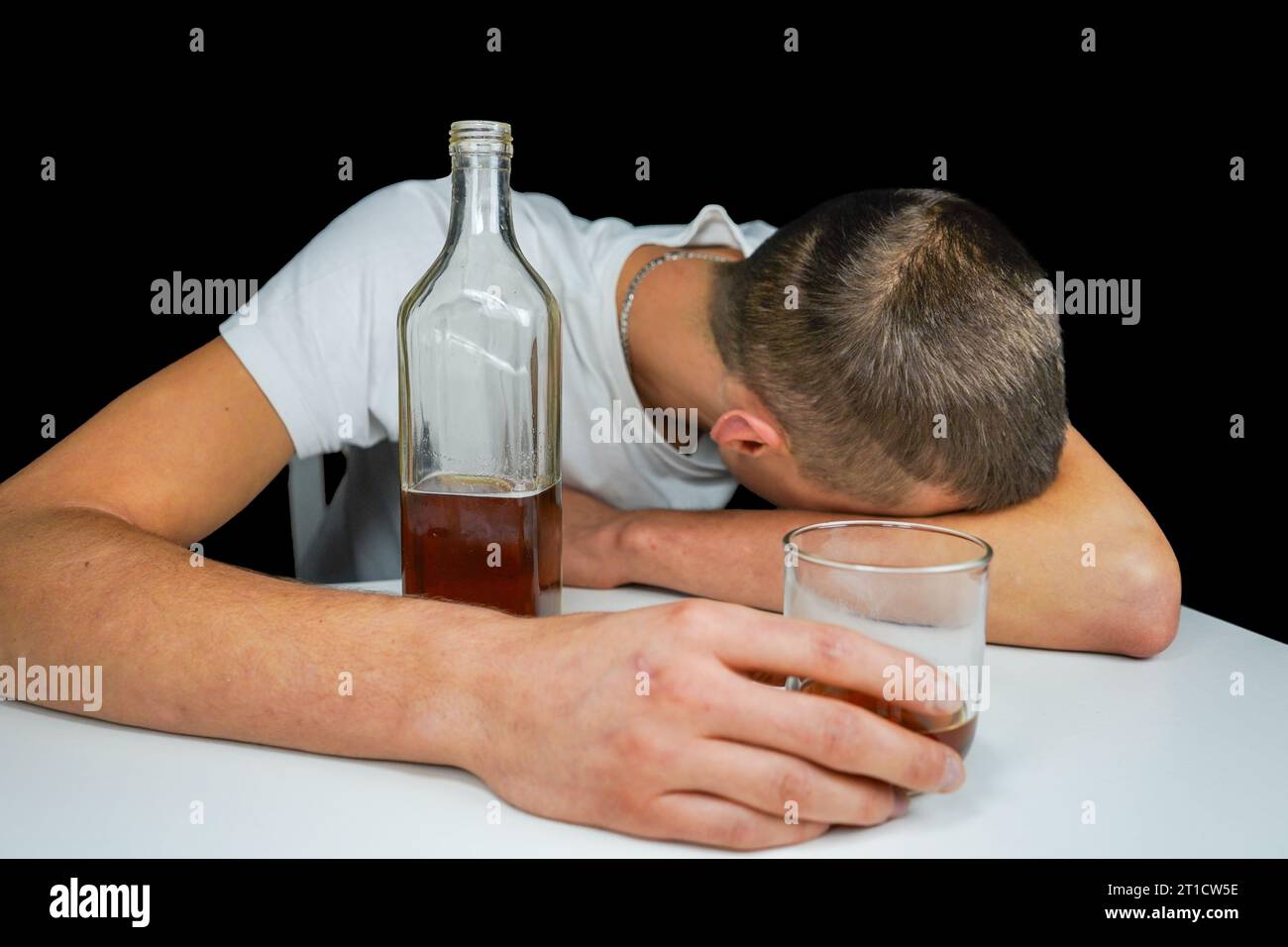 Car keys and alcohol on the table. Drunk man sleeping on the table with bottle of whiskey and drink. Alcoholism. Don't drive when you're drunk. Stock Photo