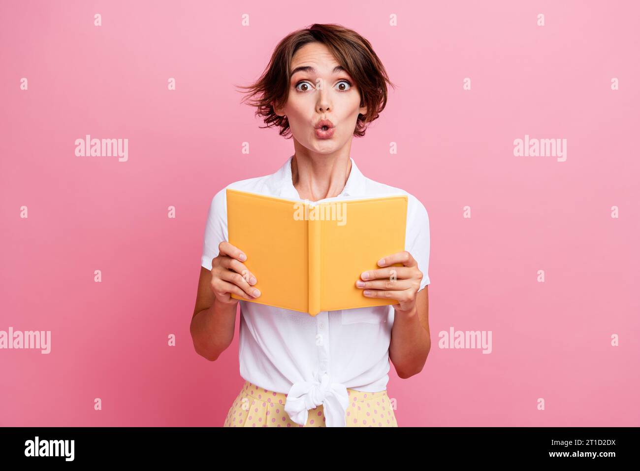 Funny impressionable young girl photo student reading new encyclopedia book surprised about world news isolated on pink color background Stock Photo