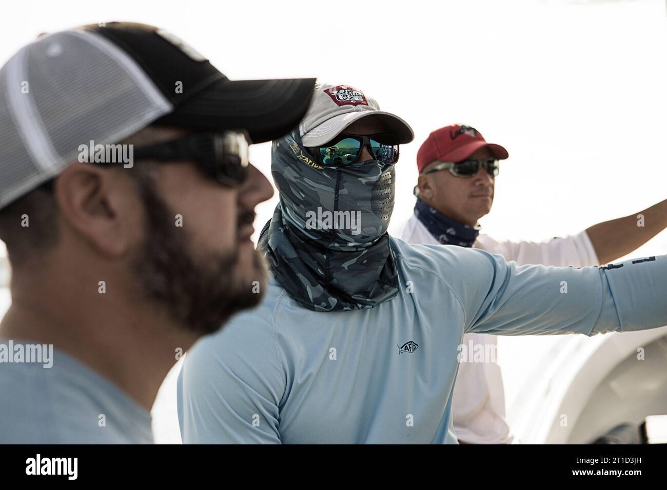 Three fishermen with sunglasses look off at the water. Stock Photo