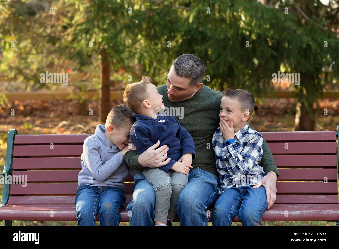 Father on a bench, engaged in a heartwarming interaction with his sons Stock Photo