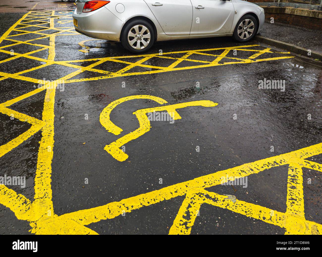 yellow road markings on the road to identify multiple diabled parking spaces in the UK.  Disabled parking sign. Parking for disabled, handicapped citi Stock Photo