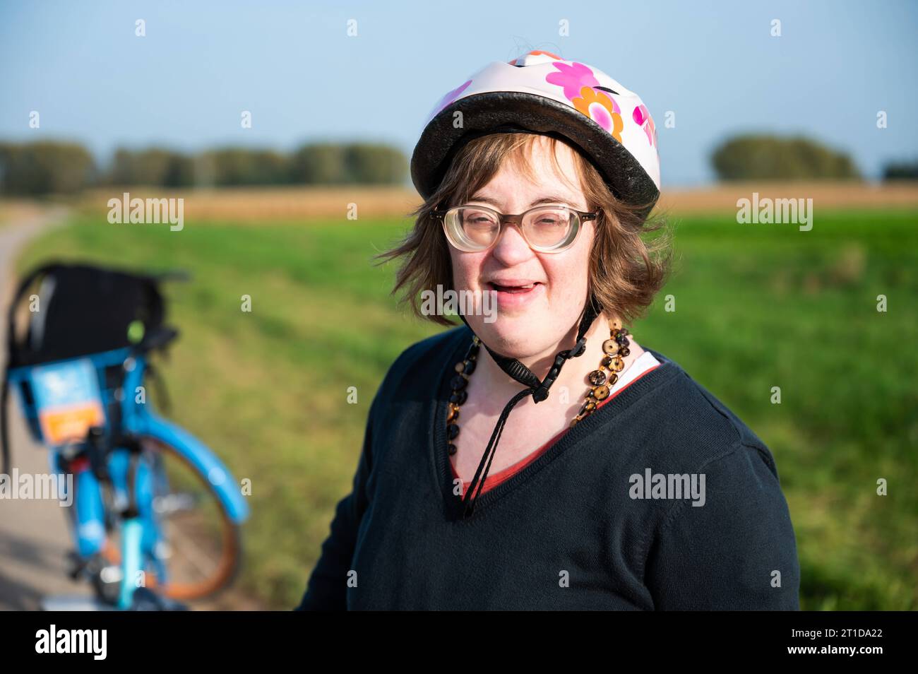 Smiling 41 yo woman with the Down Syndrome, wearing a bike helmet