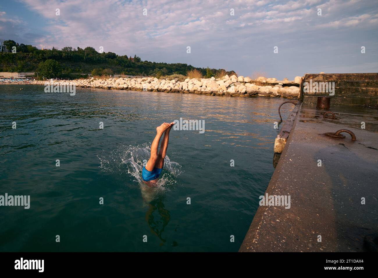 8 years old boy dives into the sea from a pier. Hot summer day Stock ...