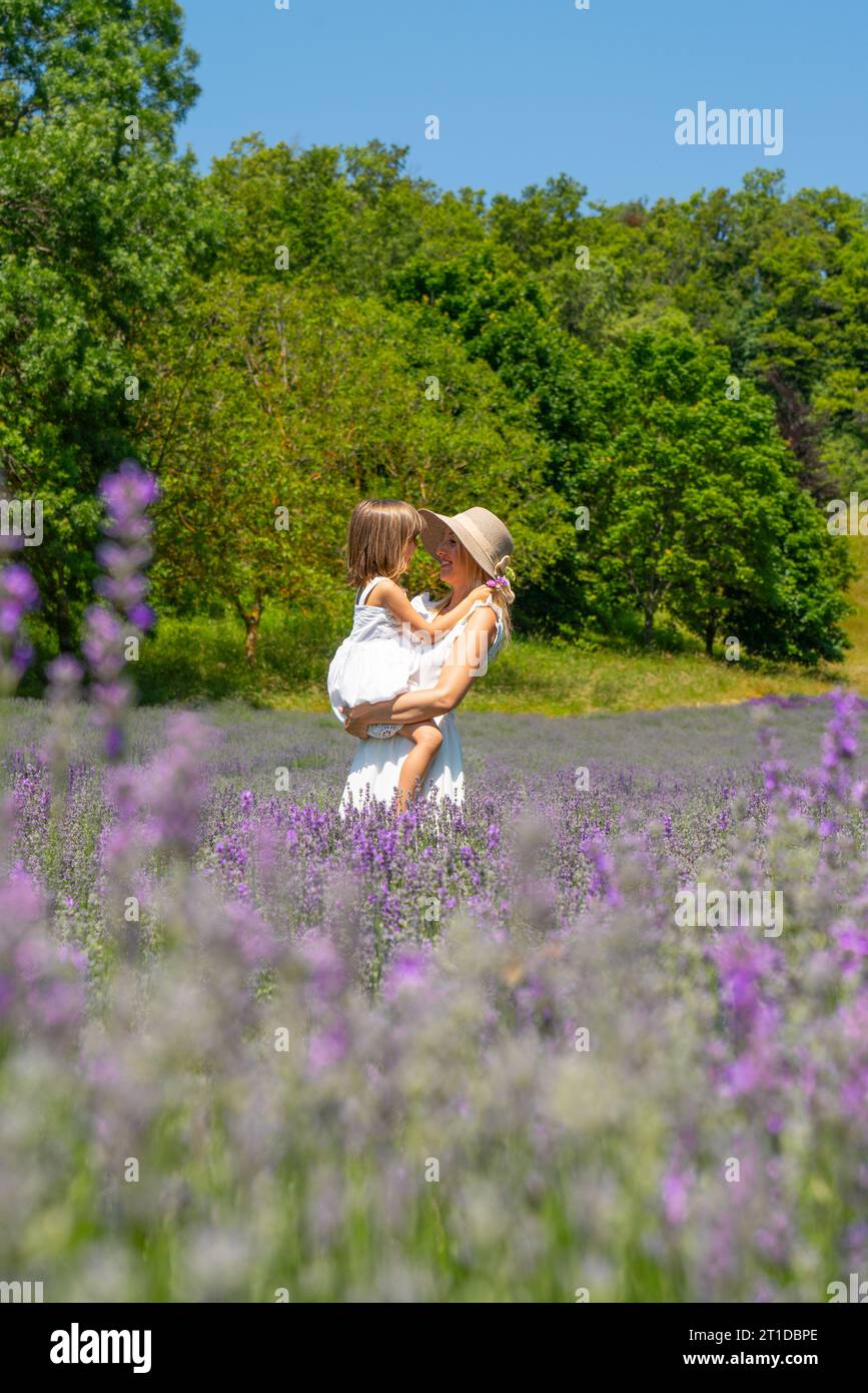 Pretty young woman wearing hat in a lavender field with her young baby daughter Stock Photo