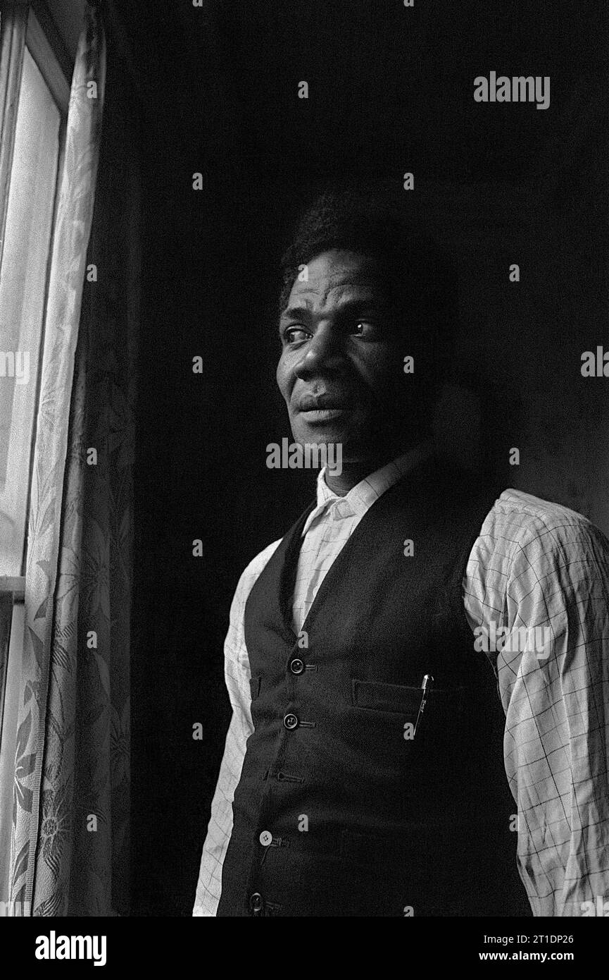 Black man stood in the window of his Victorian terraced house during