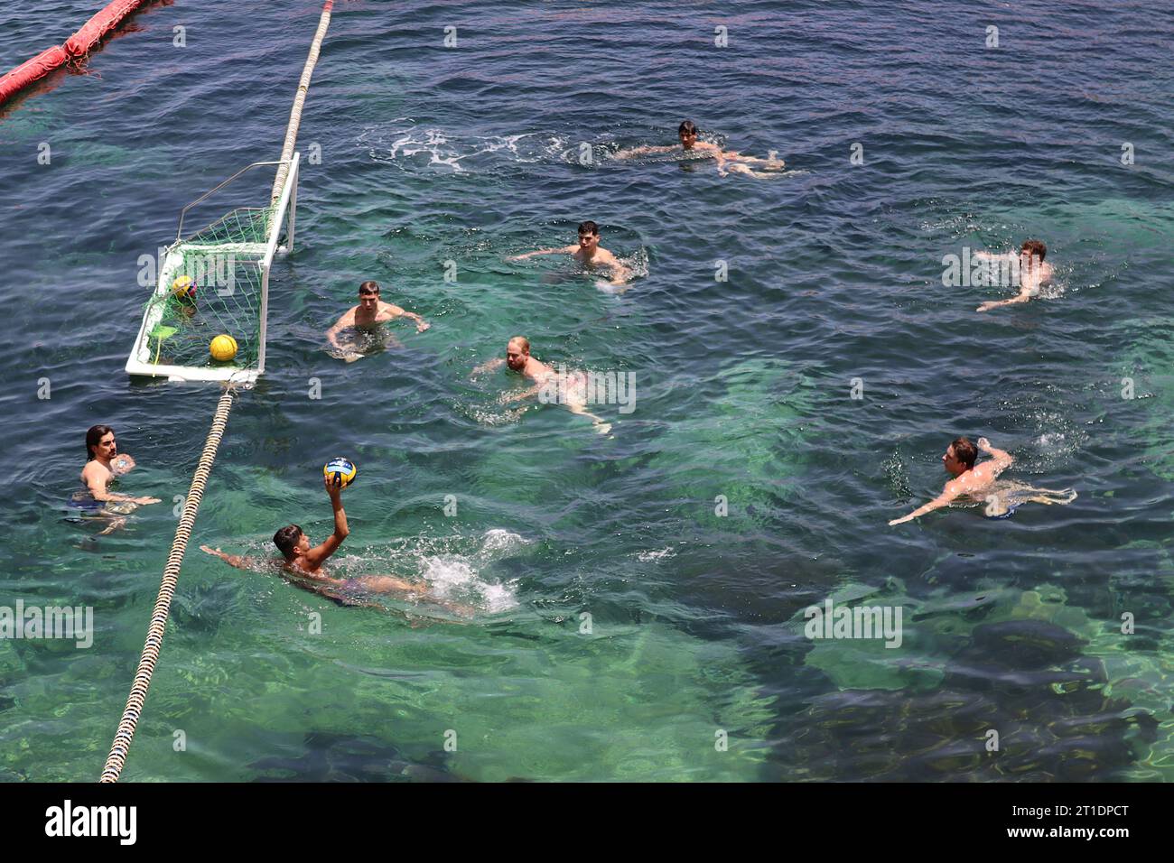 Water polo players swifty pass the ball during a training session in a sectioned off part of the Mediterranean at Marsalforn, Gozo, Malta, June 2022. Stock Photo