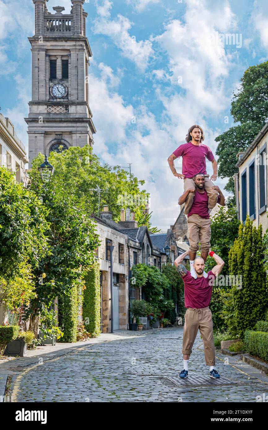 Barely Methodical Troupe acrobats standing on shoulders in picturesque mews cobbled road of Circus Lane, Edinburgh, Scotland, UK Stock Photo