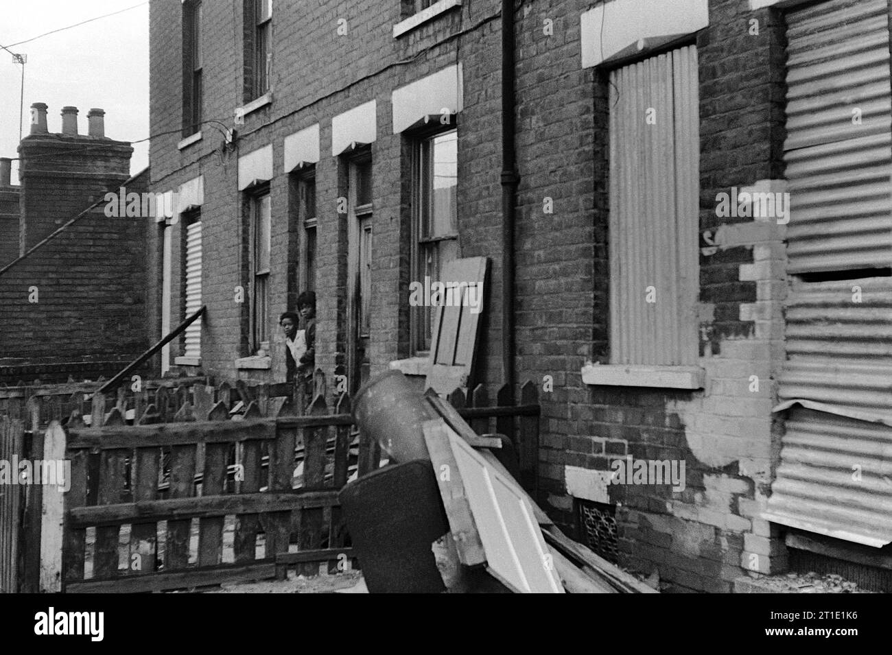Two black children looking out from their Victorian terraced house during the slum clearance and demolition of St Ann's, Nottingham. 1969-1972 Stock Photo
