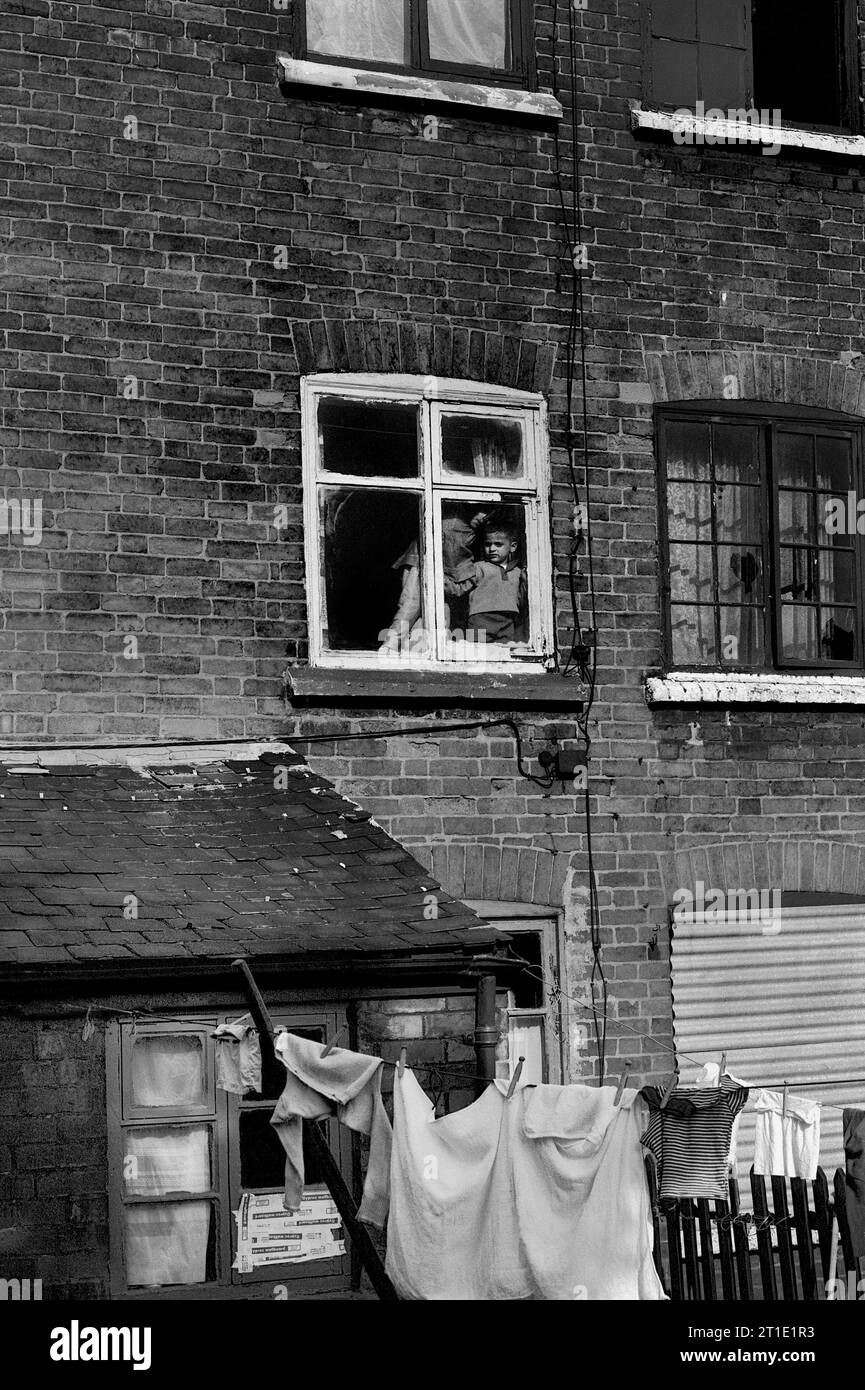 Two children looking out the bedroom window of their Victorian terraced house during slum clearance and demolition of St Ann's, Nottingham. 1969-1972 Stock Photo