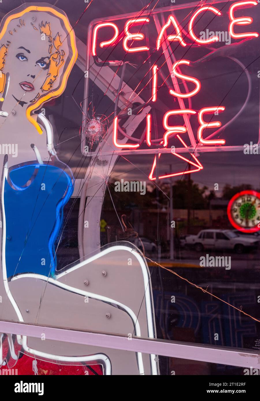 Front window of a neon sign shop with bullet hole in Albuquerque, New