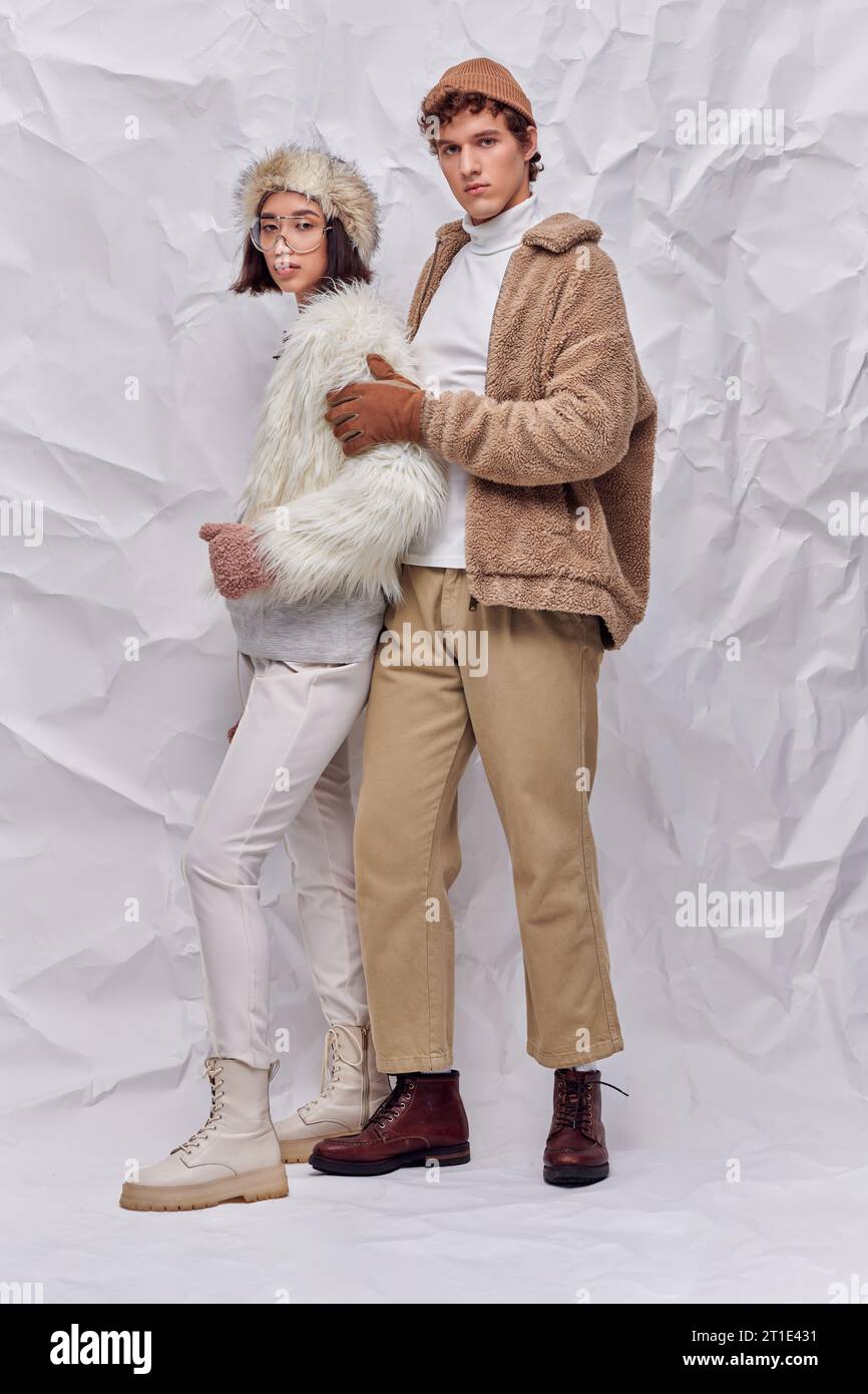 young stylish man embracing asian woman in faux fur jacket and ...