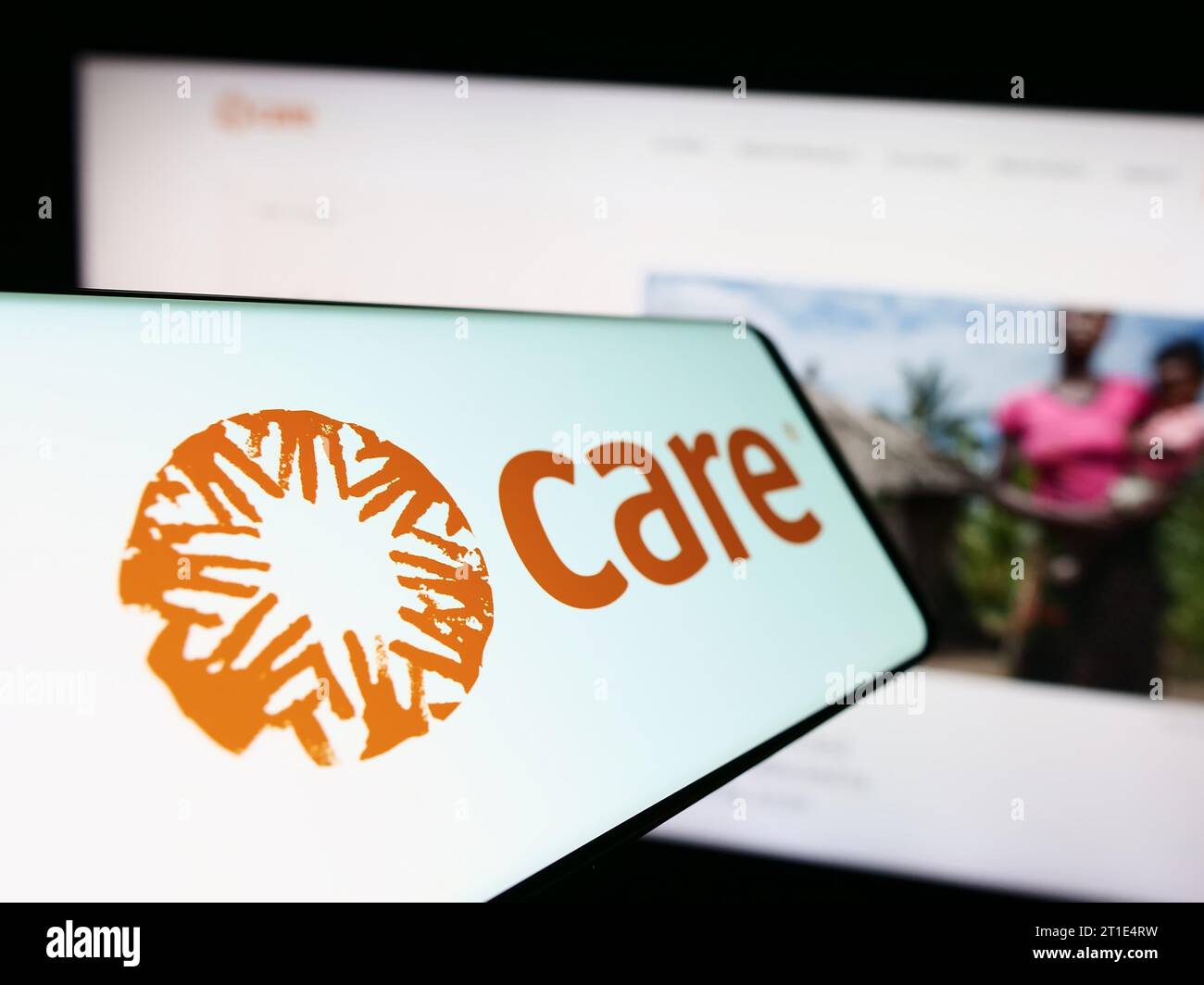 Smartphone with logo of humanitarian agency CARE International in front of website. Focus on center-left of phone display. Stock Photo