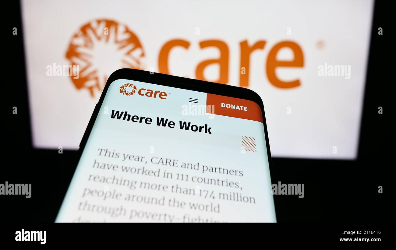 Mobile phone with website of humanitarian agency CARE International in front of logo. Focus on top-left of phone display. Stock Photo