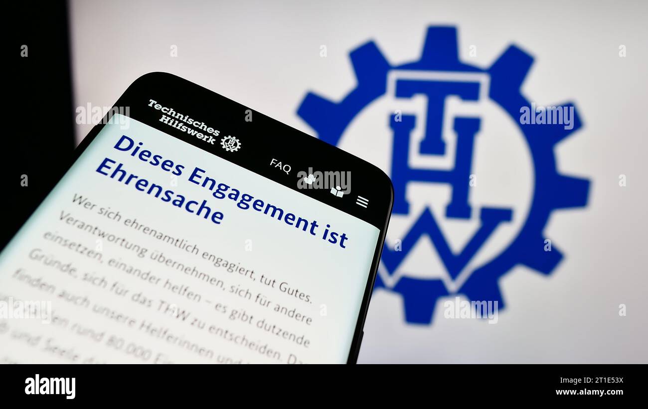 Smartphone with webpage of organization Bundesanstalt Technisches Hilfswerk (THW) in front of logo. Focus on top-left of phone display. Stock Photo
